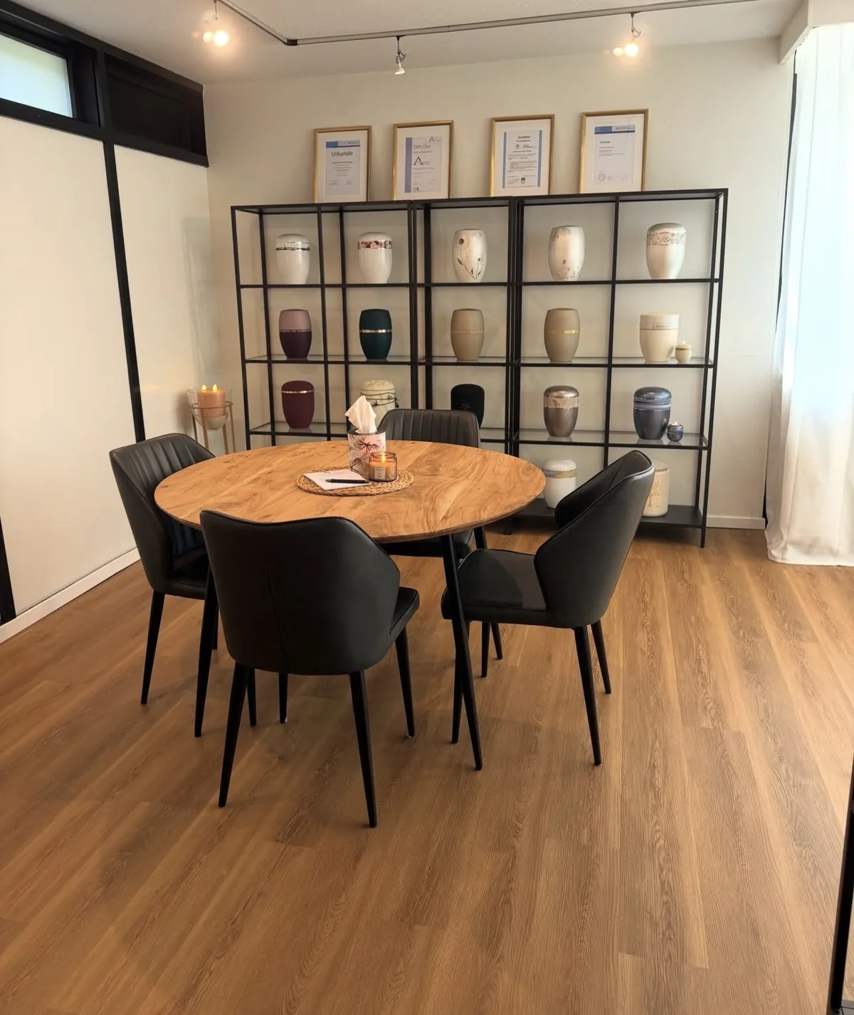 Besprechungszimmer mit rundem Tisch und Regal mit Urnen im Bestattungshaus Prange