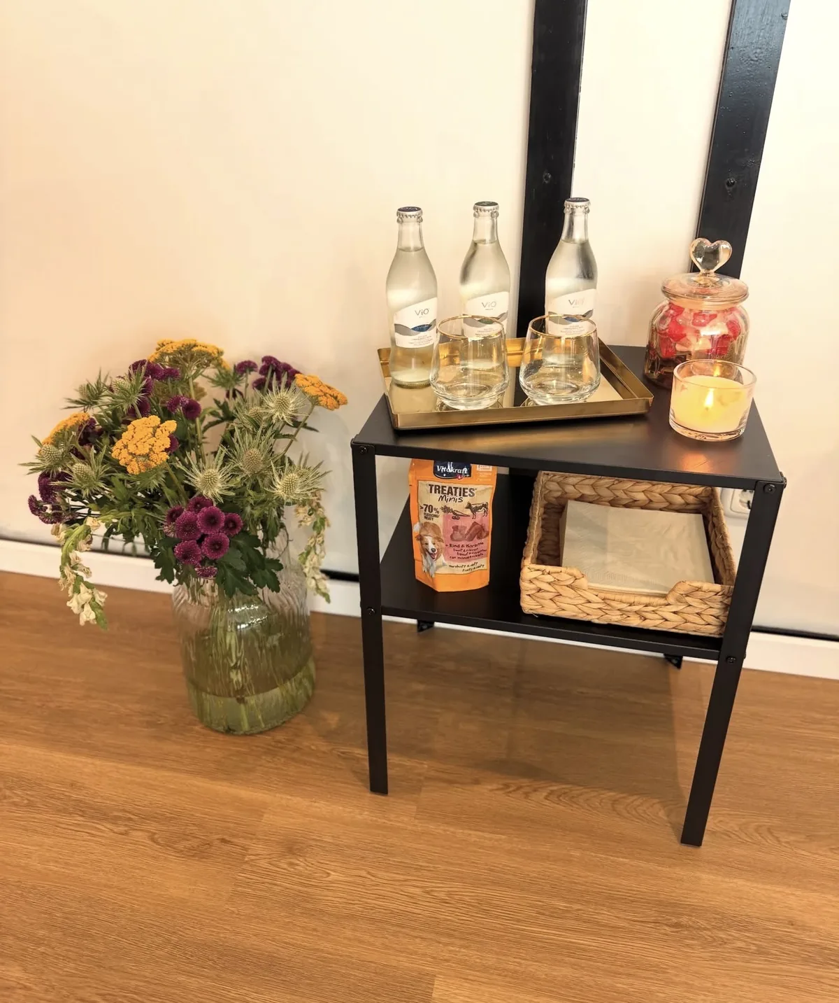 Beistelltisch mit Wasser, Gläsern, Kerze und frischen Blumen im Besprechungszimmer